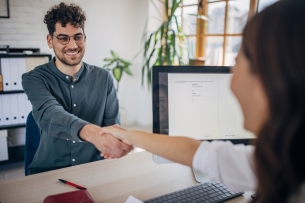 A young professional shakes the hand of a hiring manager.