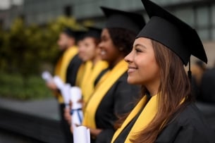 Happy group of graduating students in a row holding their diplomas