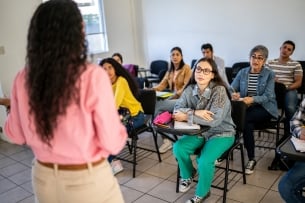 View looking over shoulder of young instructor facing a classroom of seated college students 