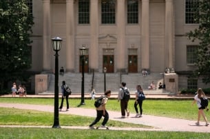 Students mill about in front of a library on a college campus