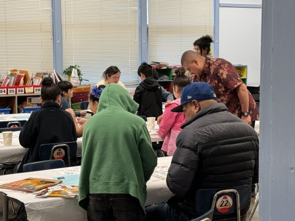 Children and adults in an elementary school classroom read a bilingual book