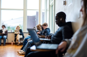 Students at Goucher College work in a well-lit room at individual desks on their laptops.